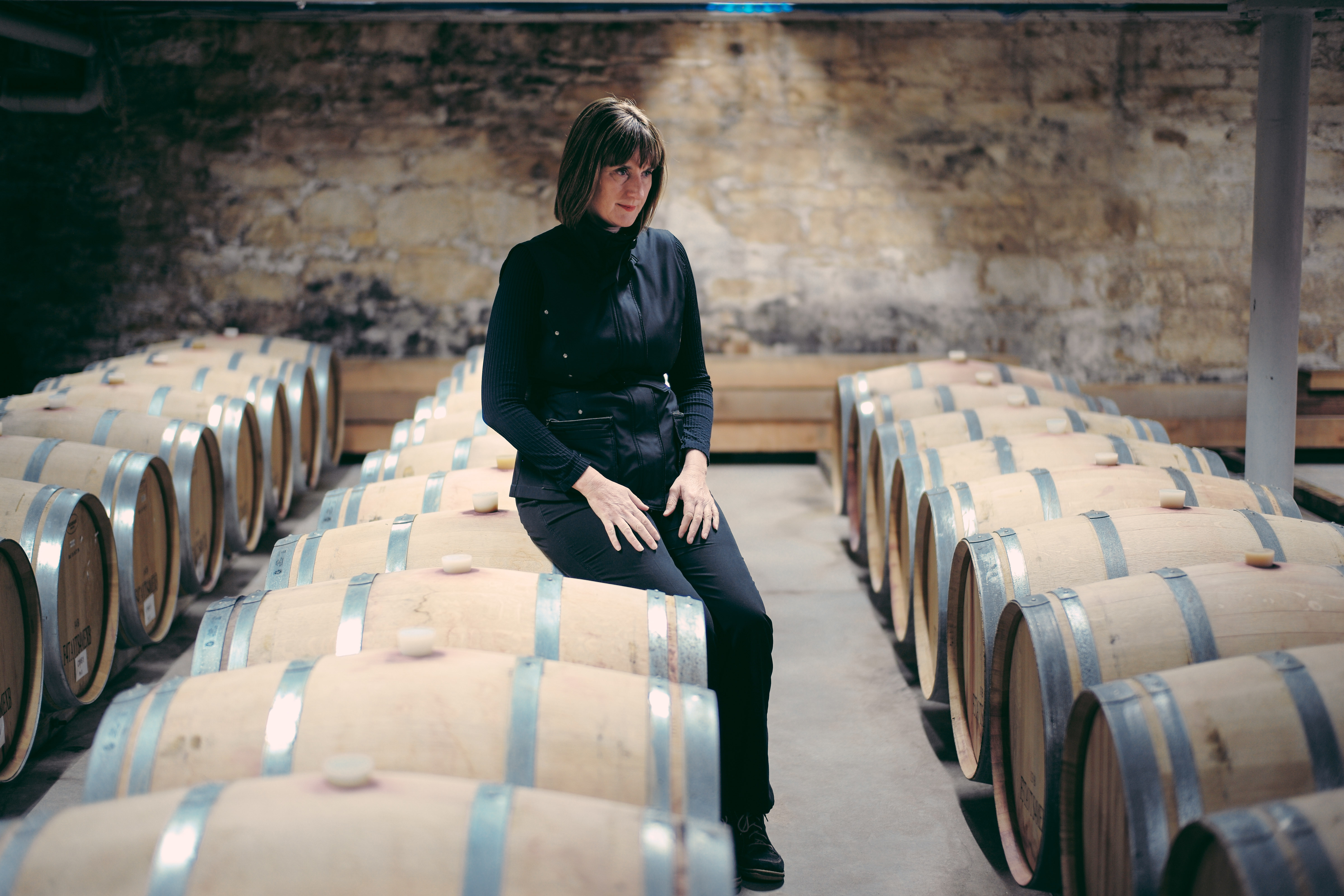 Woman sittting on a barrel surounded by barrels 